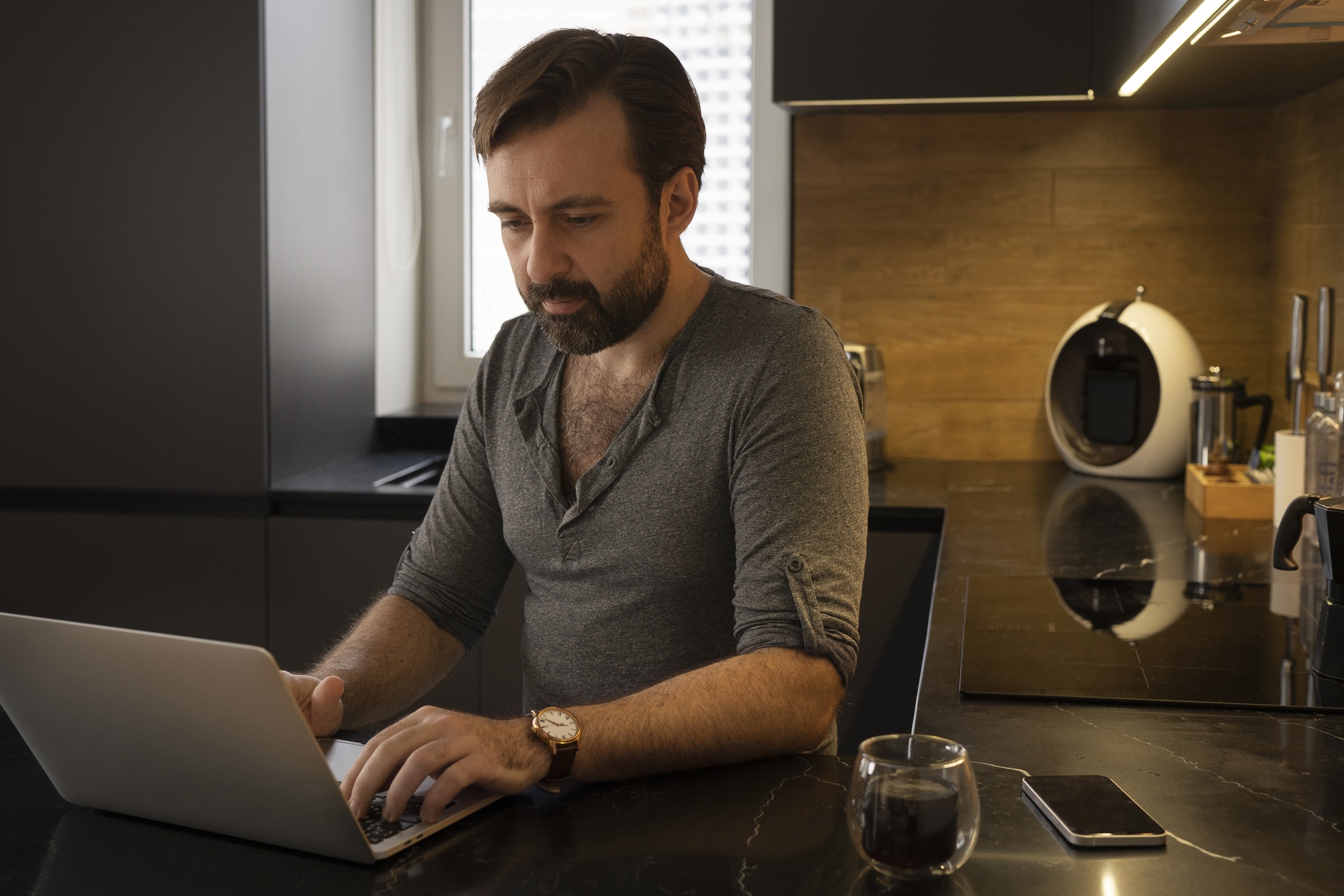Vállalkozó otthon a laptopján dolgozik, mellette a telefonja